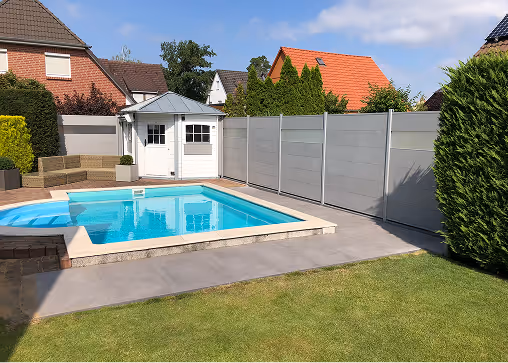 Moderner Garten mit blauem Schwimmbecken, grauer Terrasse, weißen Gartenhäuschen und hohem Sichtschutzzaun.
